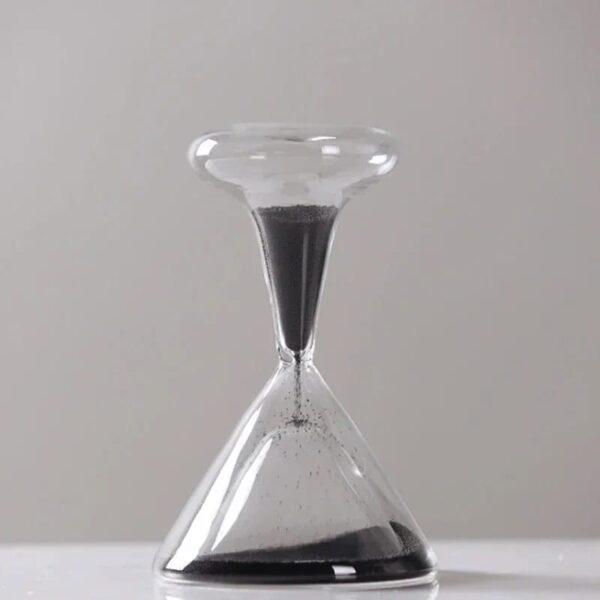 An hourglass with black sand flowing through a clear glass frame, used for measuring time in science experiments and educational activities.