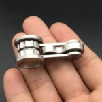Small metallic chain link model held on fingers, showcasing a detailed miniature chain for science and engineering education.