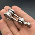 Small metallic mechanical linkage model held in hand, used for science demonstrations and educational purposes.