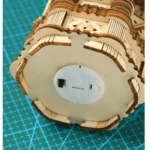 Detailed view of a miniature wooden mechanical model kit, showcasing intricate laser-cut parts assembled on a green cutting mat, perfect for science and engineering projects.