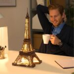 Man enjoying a warm drink while sitting at a desk with a detailed Eiffel Tower LED lamp, perfect for science decor and educational spaces.