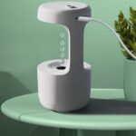Modern water dispenser with LED indicator lights and a sleek design, placed on a pastel green table next to a potted plant.