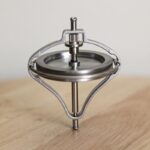 A spinning top toy demonstrating physics principles with a sleek metallic design.