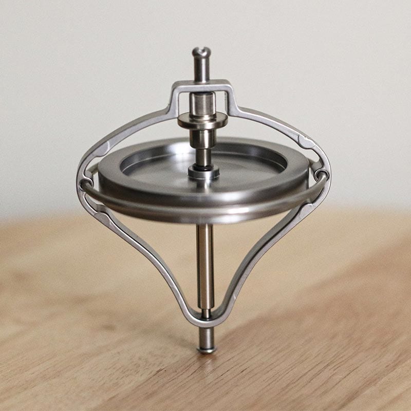 A spinning top toy demonstrating physics principles with a sleek metallic design.