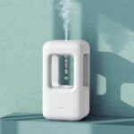 A compact white humidifier emitting a gentle mist with water droplets falling inside a transparent chamber, designed for educational and decorative purposes.