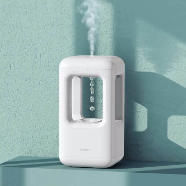 A compact white humidifier emitting a gentle mist with water droplets falling inside a transparent chamber, designed for educational and decorative purposes.