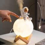 Moon-shaped lamp with astronaut figurine and hanging star, perfect for science-themed decor and educational spaces.