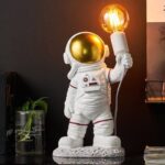Cute astronaut figurine holding a glowing light bulb, perfect as a decorative piece or educational toy for space enthusiasts.