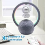 Space-themed desk lamp featuring a moon base design with a spherical astronaut figure and a circular LED ring. Includes Bluetooth 5.0 connectivity for wireless audio.