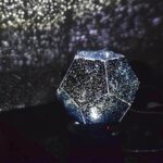Illuminated geometric dodecahedron lamp emitting a starry, galaxy-like glow in a dark room, creating a mesmerizing cosmic ambiance.