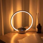 Modern glow ring LED lamp with touch control, placed on a wooden surface, creating ambient lighting in a cozy room setting.