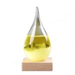 A glass dropper with yellow liquid on a wooden base, used for science experiments and educational demonstrations.