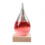Liquid dropper science toy with a glass teardrop-shaped container filled with red liquid, mounted on a wooden base for educational experiments and decorative purposes.