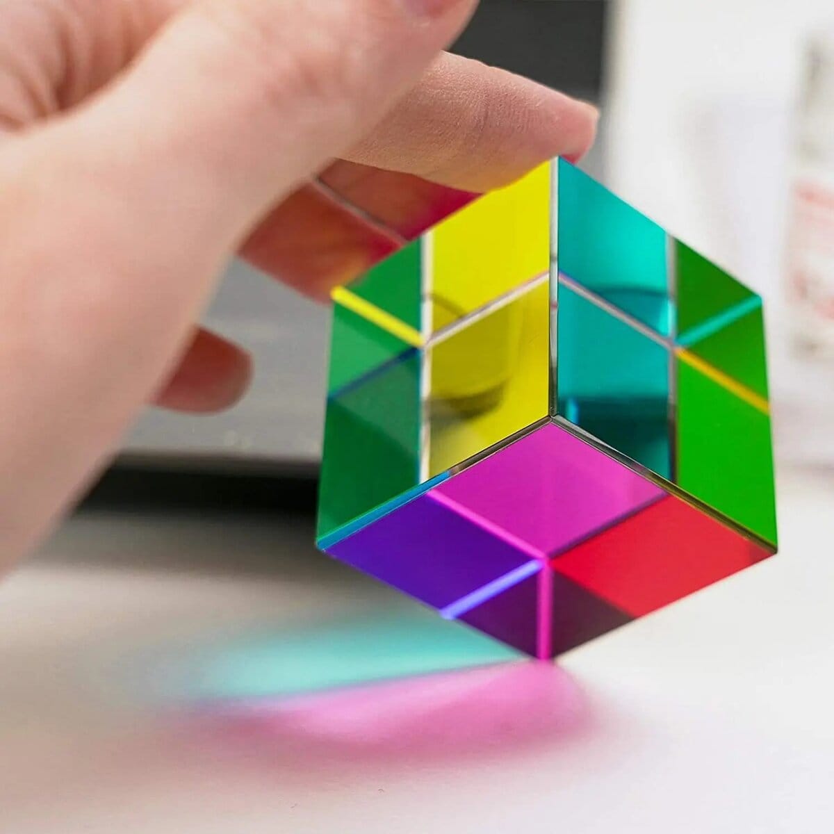 Colorful Geometric Cube Puzzle Hand holding a vibrant, multicolored geometric cube puzzle with reflective surfaces, showcasing a modern educational toy for science and math enthusiasts.