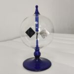 A glass sphere with a blue stand and two floating metallic squares inside, demonstrating magnetic levitation.