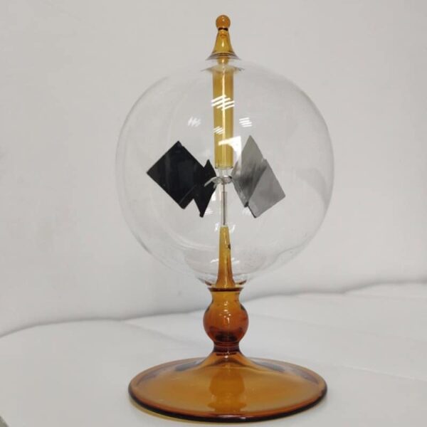 Small Tesla coil model demonstrating electrostatic principles with a glass sphere, metal electrodes, and a wooden base, used for educational science demonstrations.