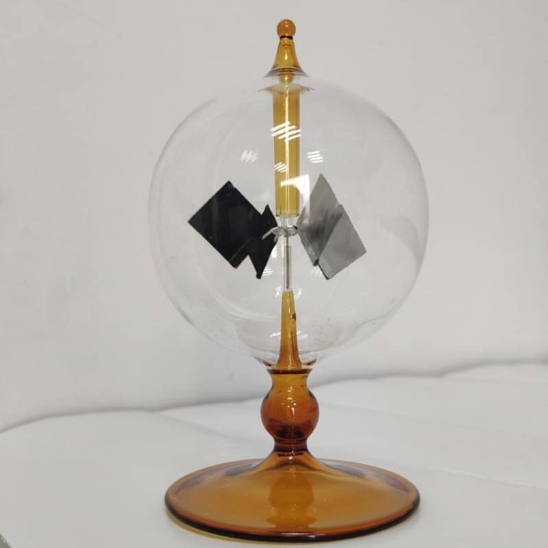 Small Tesla coil model demonstrating electrostatic principles with a glass sphere, metal electrodes, and a wooden base, used for educational science demonstrations.