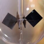 Close-up of a magnetic levitation experiment showing two black magnetic objects suspended in mid-air within a transparent container.