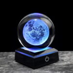 Illuminated moon globe night light with a glowing blue surface, placed on a black base with power button, ideal for science decor and educational purposes.