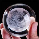 Hand holding a glass moon globe crystal ball showing detailed lunar surface, ideal for science decor and educational toys.
