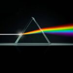 A triangular glass prism dispersing white light into a spectrum of colors, demonstrating light refraction and dispersion principles.