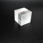 Transparent glass cube with optical illusion effect on a black background, showcasing a modern decorative and educational science gadget.