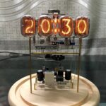 Vintage nixie tube digital clock showing the time 20:13:10, featuring retro-style glowing numerals and electronic components on a wooden base.