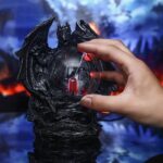 Hand holding a dragon-shaped crystal ball with LED lights, set against a mystical, fiery background. Perfect for science decor and educational toys.