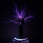 Tesla coil generating purple electrical arcs in a dark environment, showcasing high-voltage electrical phenomena for educational and science demonstration purposes.
