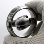 Close-up of a high-precision scientific instrument with metallic components, held by a gloved hand, showcasing detailed craftsmanship and advanced technology.