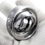 Close-up of a metallic nano rotor science toy demonstrating rotational physics, held by a gloved hand, showcasing intricate design and precision engineering.