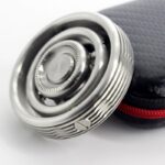 Close-up of a modern safety razor with a textured handle, placed next to a black protective case with red zipper, on a white background.