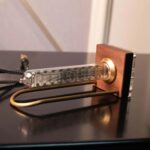 Classic analog thermometer with a glass tube, metal probe, and wooden base, used for measuring temperature in educational science experiments.