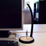 A magnetic levitation science toy demonstrating floating and spinning objects with a sleek black stand and a metallic pendulum.