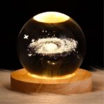 A mesmerizing galaxy scene inside a glass crystal ball, featuring a detailed miniature galaxy with stars and cosmic dust, placed on a wooden base.