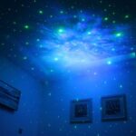Blue star projector illuminating a room with green and blue star patterns on the ceiling, creating a relaxing and magical atmosphere.