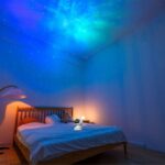 LED star projector illuminating bedroom ceiling with a starry night sky pattern, creating a relaxing and magical atmosphere for sleep or relaxation.