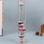 Glass water clock with floating objects and a key, demonstrating principles of time and buoyancy.