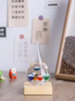 Colorful liquid-filled glass dropper with floating orbs on a wooden base, used for science experiments and educational demonstrations.