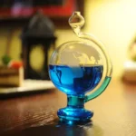 A colorful science glassware with a round bottom filled with vibrant blue liquid, placed on a wooden surface in a well-lit room.