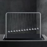 A classic Newton's Cradle with metal balls suspended on strings, demonstrating momentum and energy transfer, ideal for educational purposes and modern office decor.
