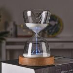 Clear glass sand timer with white sand, placed on a wooden base, used for time management, educational activities, and decorative purposes.
