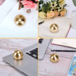 Shiny gold spherical desk ornament placed on various surfaces including a laptop, notebook, and desk with flowers, adding a modern decorative touch to workspace and home office setups.
