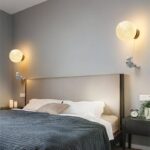 Moon and astronaut themed wall lamps providing ambient lighting in a contemporary bedroom.