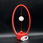 Modern Newton's Cradle with Red Frame and White Balls for Science Demonstration.