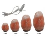 Salt lamp rocks of varying sizes with an electrical cord for demonstration purposes.
