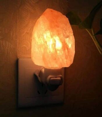 Warm Himalayan salt night light plugged into an electrical outlet, emitting a soft orange glow, perfect for creating a cozy atmosphere in any room.