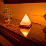 Pyramid-shaped night light emitting a warm glow on a marble surface.