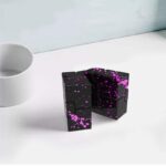 Magnetic puzzle cube with black surface and vibrant pink splatter design, perfect for educational play and brain teasers.