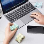 Person assembling a colorful 3D science-themed puzzle cube on a laptop desk, surrounded by educational gadgets and a smartphone, promoting STEM learning and problem-solving skills.